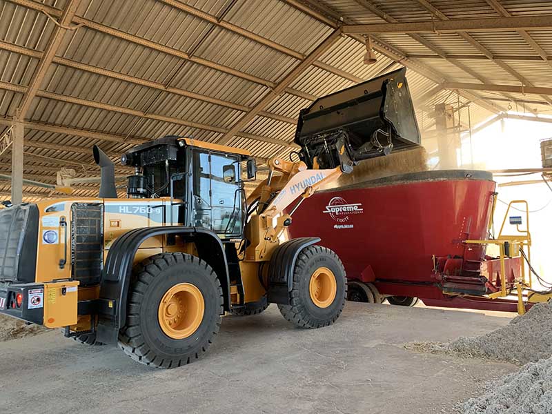 Feeding - Coggan Farms Farm Machinery pouring feed into red farm container
